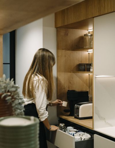 mujer haciendo café en desayunador de cocina blanca