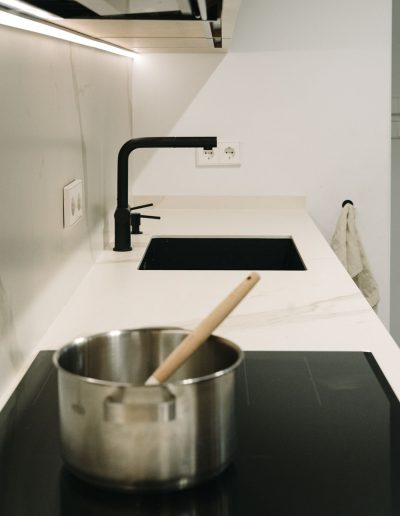 vitrocerámica fregadero y grifo negros en cocina blanca