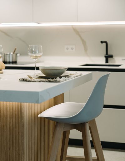 tabuerete en isla central de cocina blanca con palillería